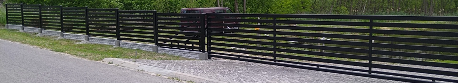 czarne długie ogrodzenie z bramą wjazdową